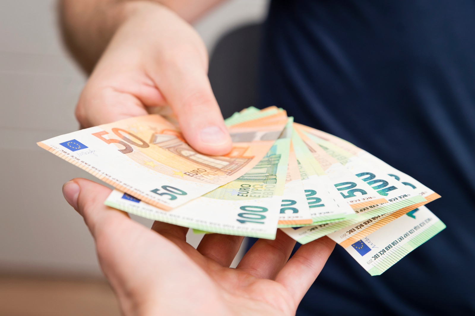 Zwei Hände die Euroscheine in der Hand haben.