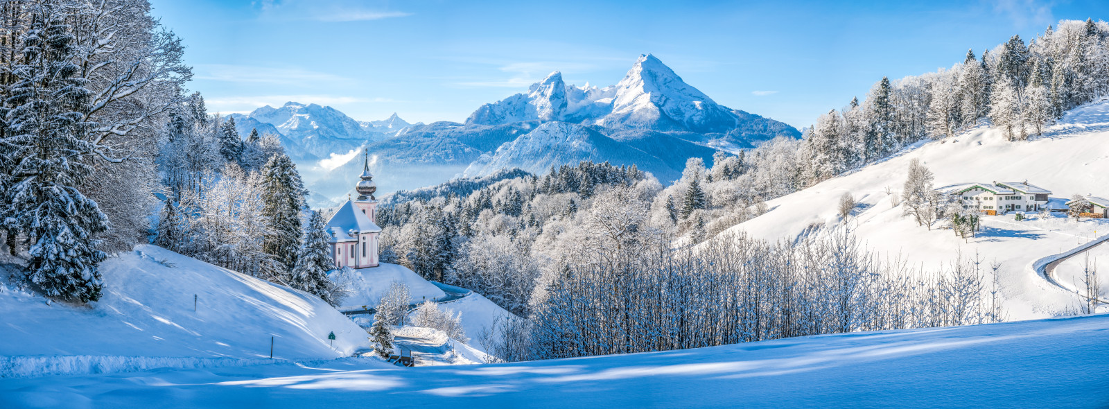 Eine verscheinte Kirche und Wiesen mit den den Alpen im Hintergrund.